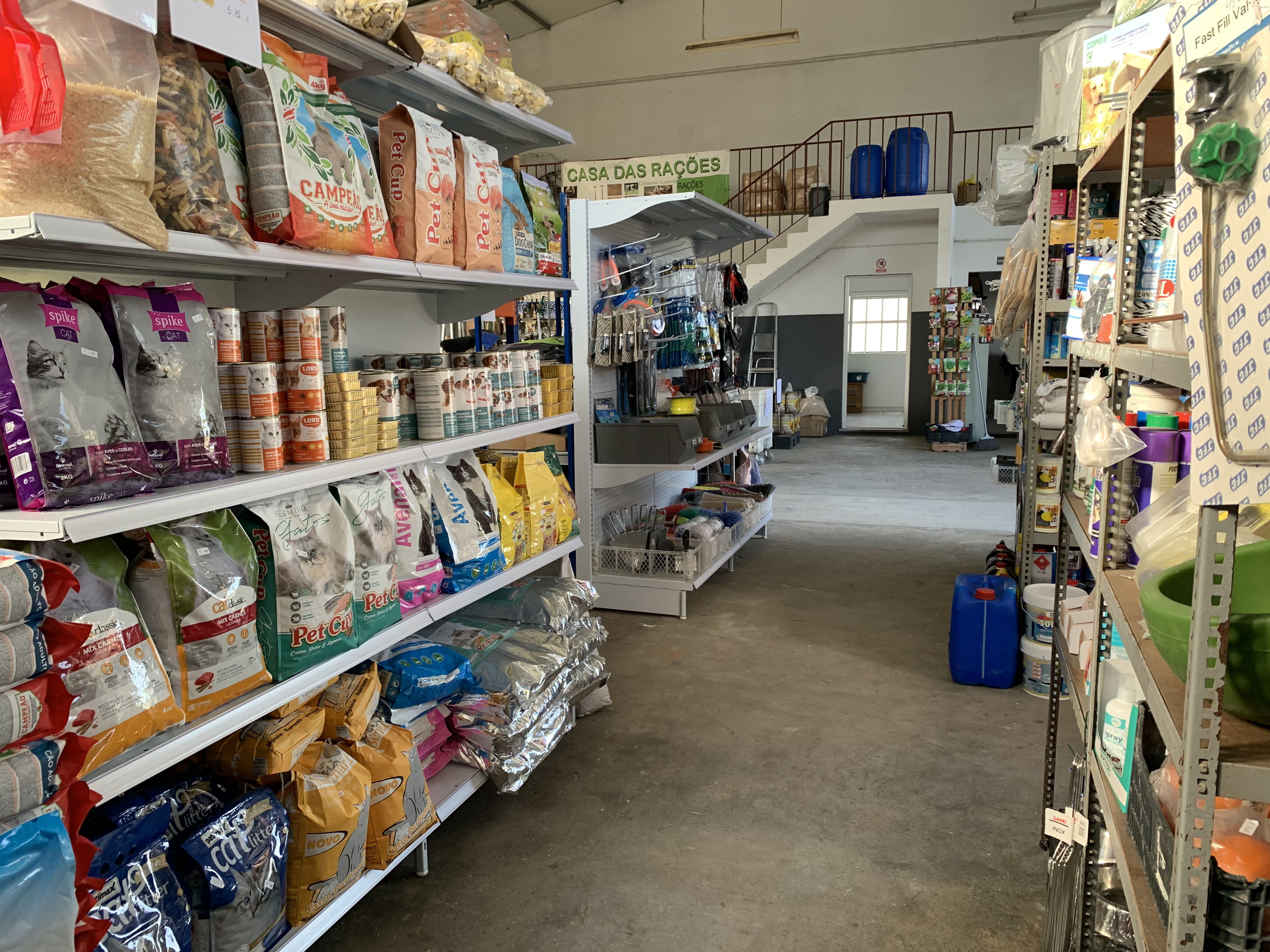 Corredor da loja com sacos de ração e artigos para animais.